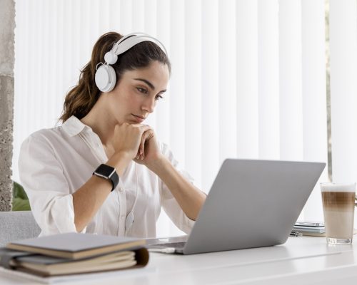 side-view-of-businesswoman-working-with-laptop-and-headphones